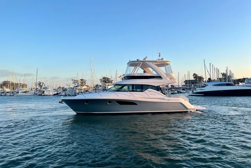 Slide: The Image of 2019 Tiara Yachts F44 Flybridge cruising in a marina at sunset. - 13