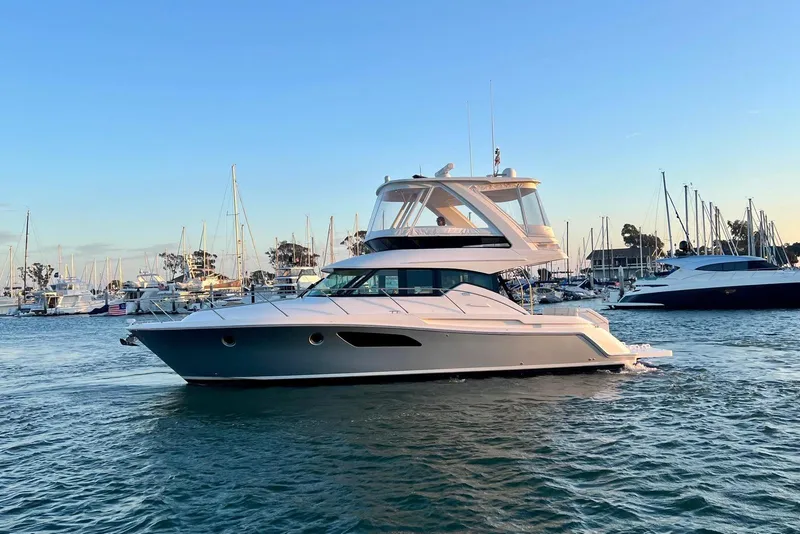 Slide: The Image of 2019 Tiara Yachts F44 Flybridge cruising in a marina at sunset. - 14