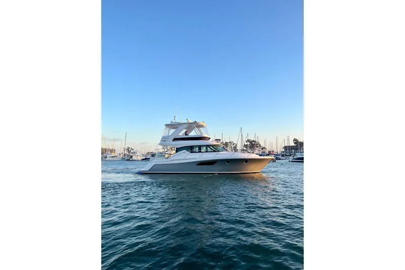 Slide: The Image of 2019 Tiara Yachts F44 Flybridge cruising in a marina at sunset. - 16