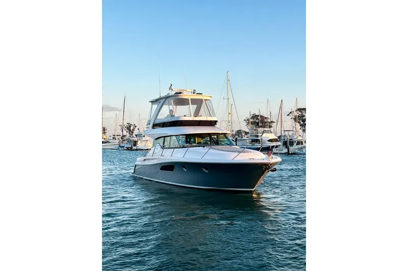 Slide: The Image of 2019 Tiara Yachts F44 Flybridge cruising in a marina at sunset. - 19