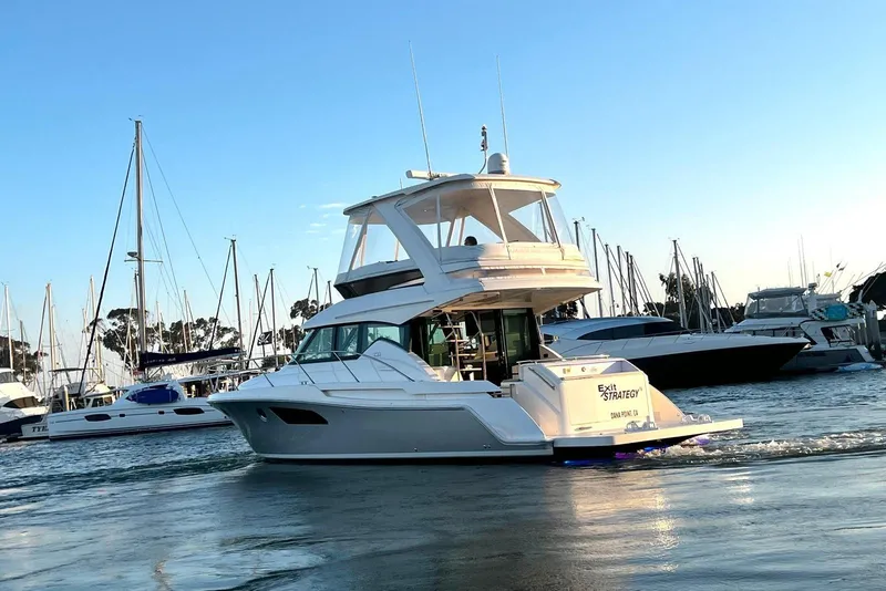 Slide: The Image of 2019 Tiara Yachts F44 Flybridge cruising in a marina at sunset. - 2