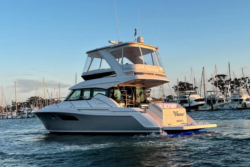 Slide: The Image of 2019 Tiara Yachts F44 Flybridge cruising in a marina at sunset. - 21