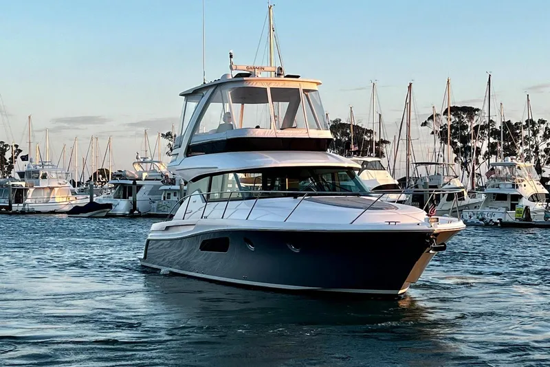 Slide: The Image of 2019 Tiara Yachts F44 Flybridge cruising in a marina at sunset. - 24