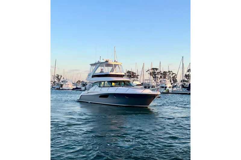 Slide: The Image of 2019 Tiara Yachts F44 Flybridge cruising in a marina at sunset. - 25