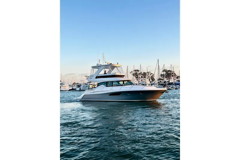 Slide: The Image of 2019 Tiara Yachts F44 Flybridge cruising in a marina at sunset. - 26