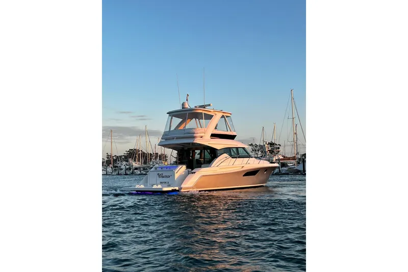 Slide: The Image of 2019 Tiara Yachts F44 Flybridge cruising in a marina at sunset. - 29