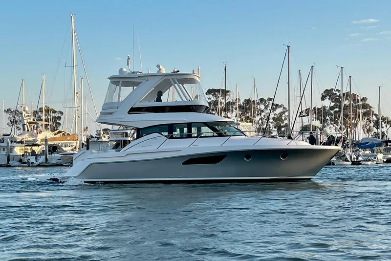 Slide: The Image of 2019 Tiara Yachts F44 Flybridge cruising in a marina with sailboats in the background. - 3