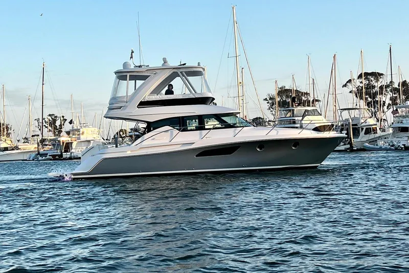 Slide: The Image of 2019 Tiara Yachts F44 Flybridge cruising in a marina with sailboats in the background. - 4