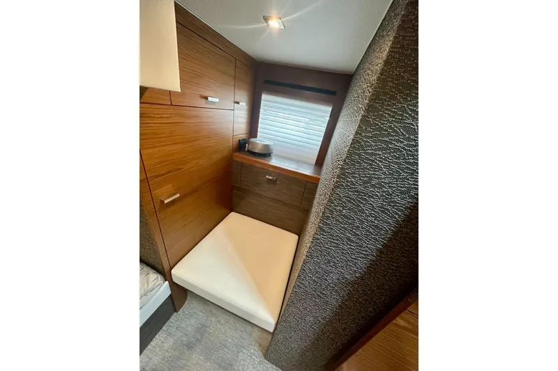 Slide: The Image of 2019 Tiara Yachts F44 Flybridge cabin interior with wood paneling and cushioned seating. - 51