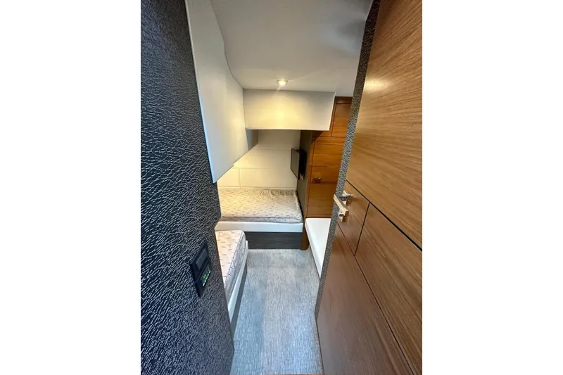 Slide: The Image of 2019 Tiara Yachts F44 Flybridge cabin interior with modern wood paneling and cozy bedding. - 61