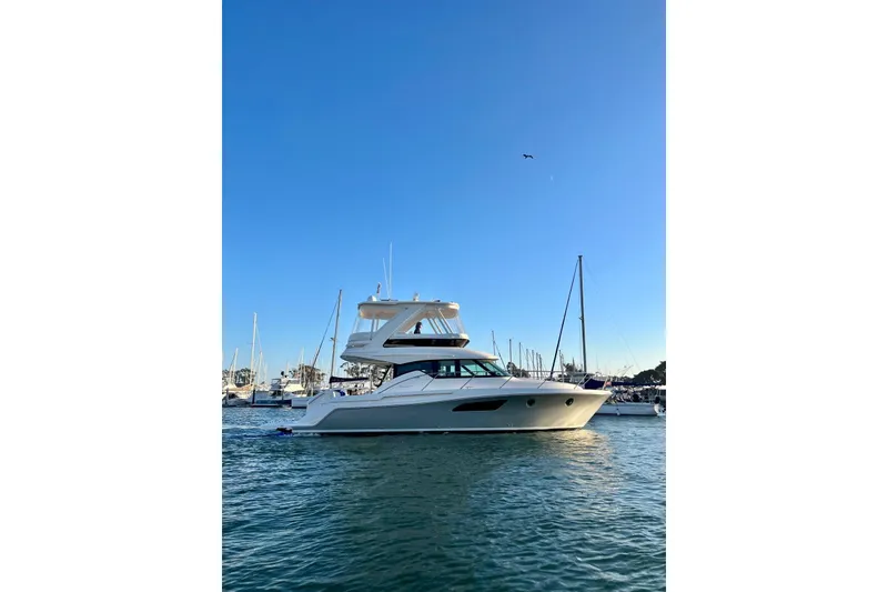Slide: The Image of 2019 Tiara Yachts F44 Flybridge on calm water, clear blue sky background. - 65