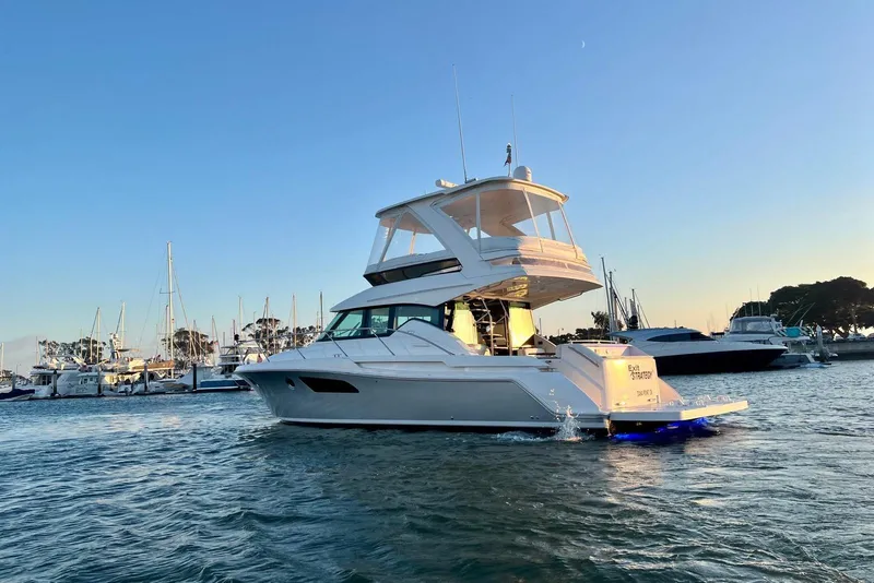 Slide: The Image of 2019 Tiara Yachts F44 Flybridge cruising in a marina at sunset. - 8