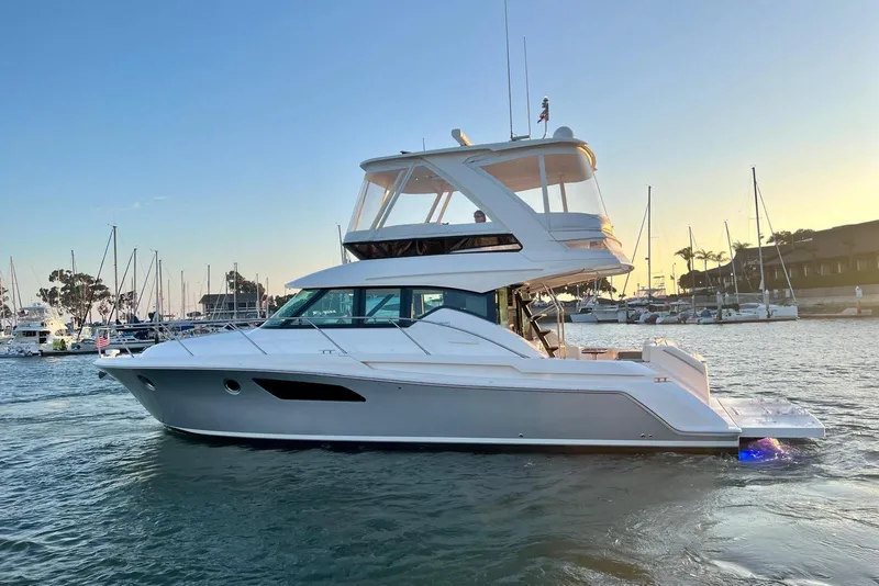 Slide: The Image of 2019 Tiara Yachts F44 Flybridge cruising in a marina at sunset. - 9