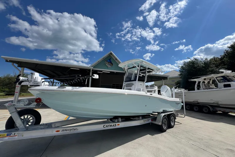 Slide: The Image of 2026 Caymas 26 HB boat on trailer under blue sky, parked near a building. - 3