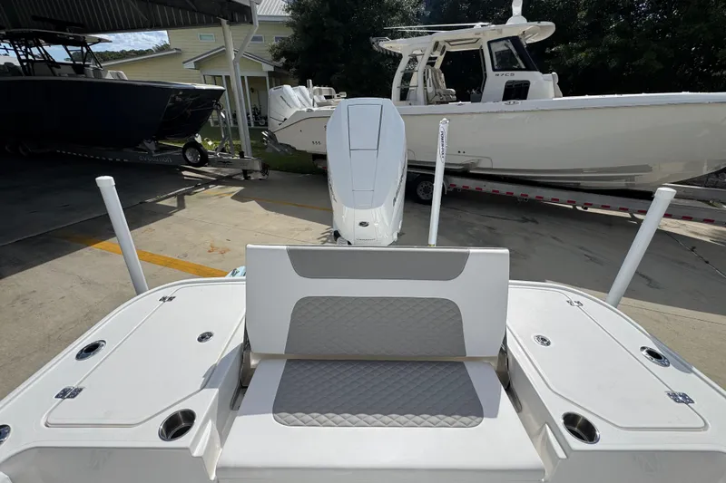 Slide: The Image of 2026 Caymas 26 HB boat with cushioned seating and outboard motor in a marina setting. - 34