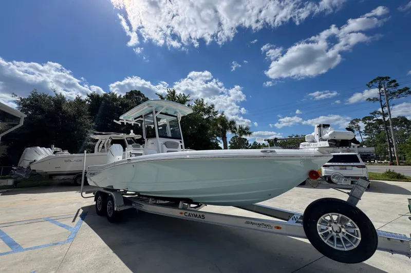 Slide: The Image of 2026 Caymas 26 HB boat on trailer under a bright blue sky with clouds. - 8