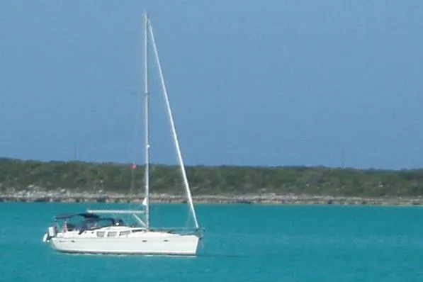 Slide: The Image of Sailboat Jeanneau Sun Odyssey 43 DS, 2002 model, on turquoise waters with distant shoreline. - 2