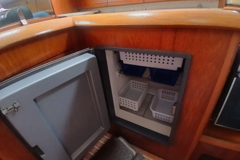 Slide: The Image of Interior of 2002 Jeanneau Sun Odyssey 43 DS showing open fridge with storage baskets. - 24