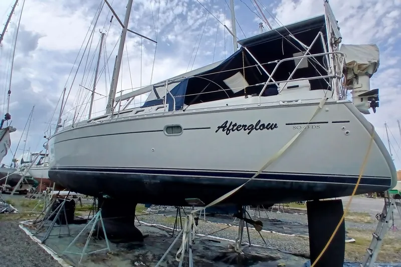 Slide: The Image of 2002 Jeanneau Sun Odyssey 43 DS sailboat on dry dock, named "Afterglow," under a cloudy sky. - 4