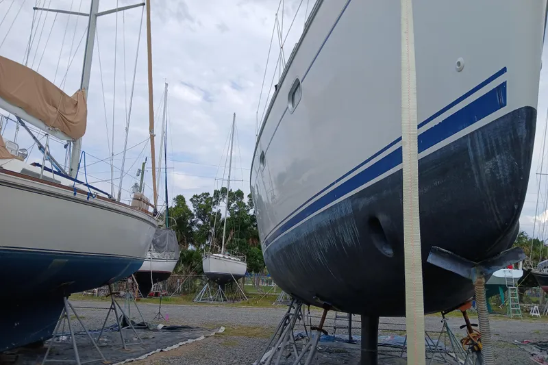 Slide: The Image of Jeanneau Sun Odyssey 43 DS sailboat from 2002 on dry dock, surrounded by other boats. - 57