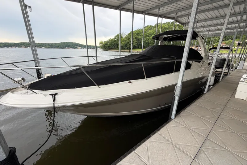 The Image of 2007 Sea Ray Sundancer 320 docked under a covered marina, featuring sleek design and black cover. - 0