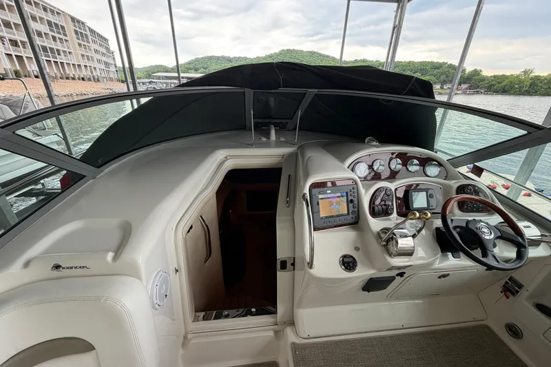 Slide: The Image of 2007 Sea Ray Sundancer 320 cockpit with navigation controls and steering wheel, docked by the water. - 14