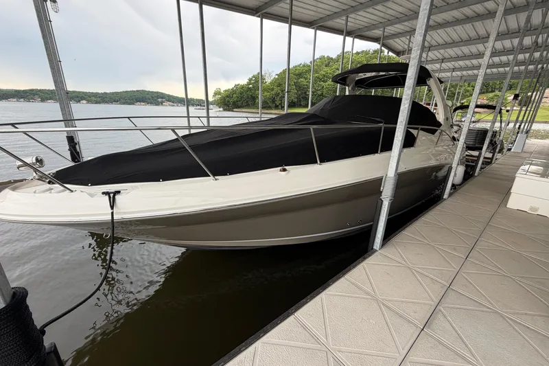 Slide: The Image of 2007 Sea Ray Sundancer 320 docked under a covered marina, featuring sleek design and black cover. - 2