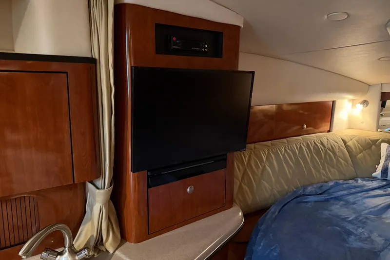 Slide: The Image of 2007 Sea Ray Sundancer 320 cabin interior with TV, wood paneling, and cozy bedding. - 27