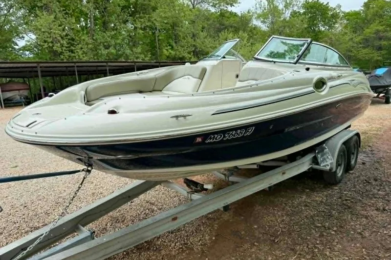 The Image of 2006 Sea Ray 240 Sundeck boat on trailer, parked outdoors with trees in background. - 0