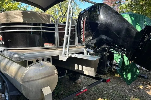 The Image of 2022 SUNTRACKER 22 DLX pontoon boat with Mercury outboard motor, parked outdoors. - 1
