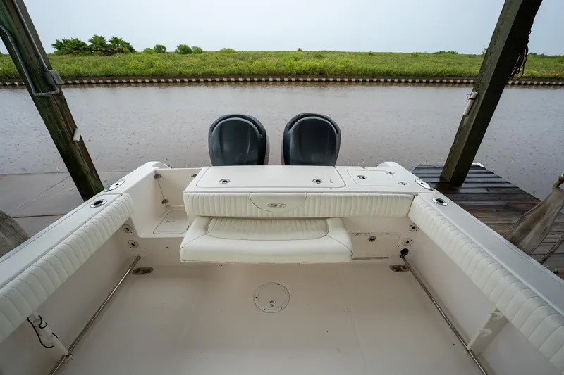 Slide: The Image of 2007 Sea Hunt Triton 290 boat interior with seating and twin engines by a dock. - 13