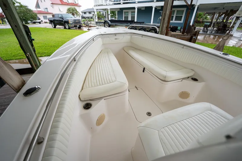 Slide: The Image of 2007 Sea Hunt Triton 290 boat interior with white cushioned seating, parked near a house. - 29