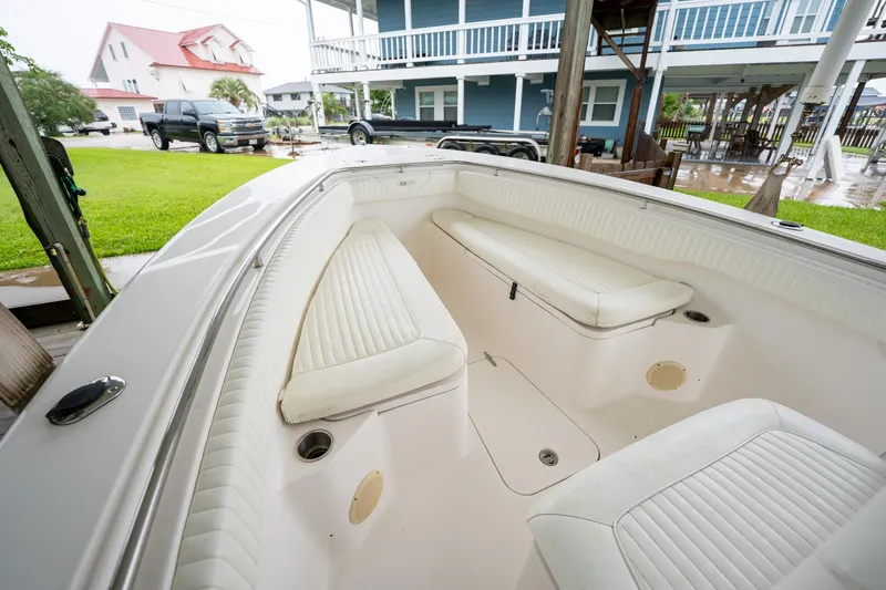Slide: The Image of 2007 Sea Hunt Triton 290 boat interior with white seating, parked near houses. - 30