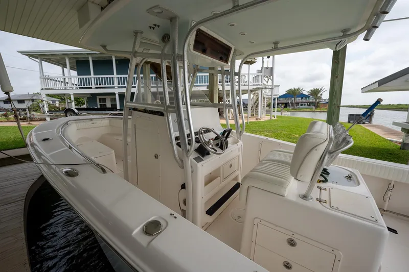 Slide: The Image of 2007 Sea Hunt Triton 290 boat interior with steering console, docked near waterfront homes. - 4