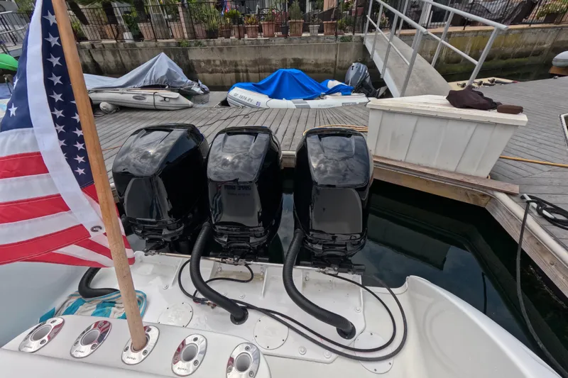 Slide: The Image of 2011 Donzi 38 ZFX Open with triple outboard engines docked, featuring an American flag. - 19
