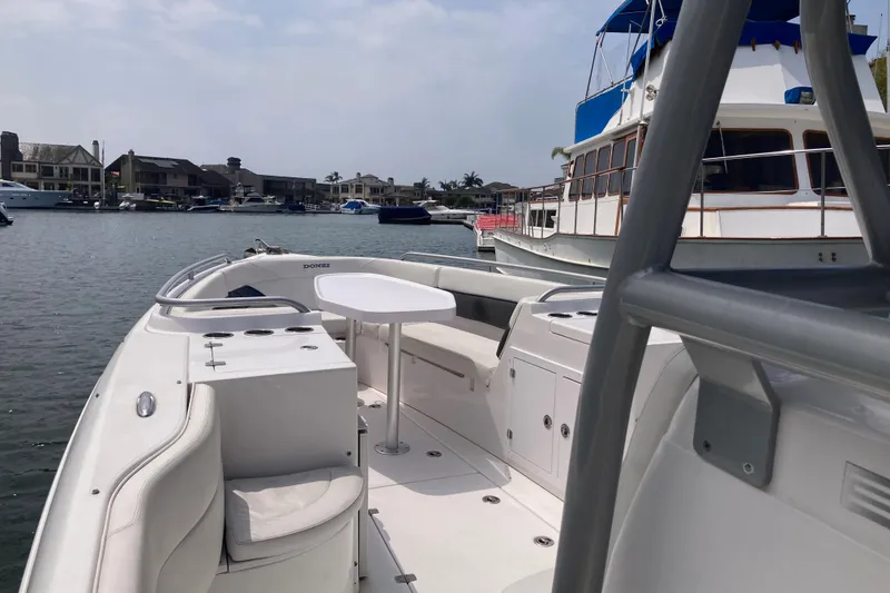 Slide: The Image of 2011 Donzi 38 ZFX Open boat with spacious seating and table, docked in a marina. - 38