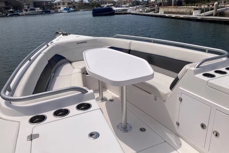 Slide: The Image of 2011 Donzi 38 ZFX Open boat interior with seating and table, docked in a marina. - 39