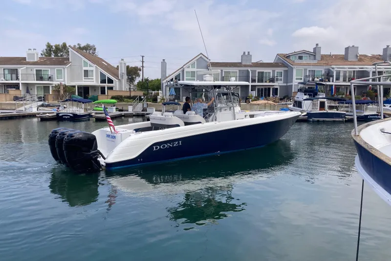 Slide: The Image of 2011 Donzi 38 ZFX Open boat cruising in a marina with waterfront homes. - 5