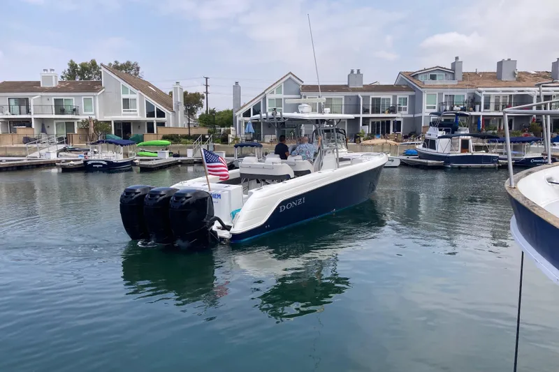 Slide: The Image of 2011 Donzi 38 ZFX Open boat cruising in a marina with waterfront homes. - 6