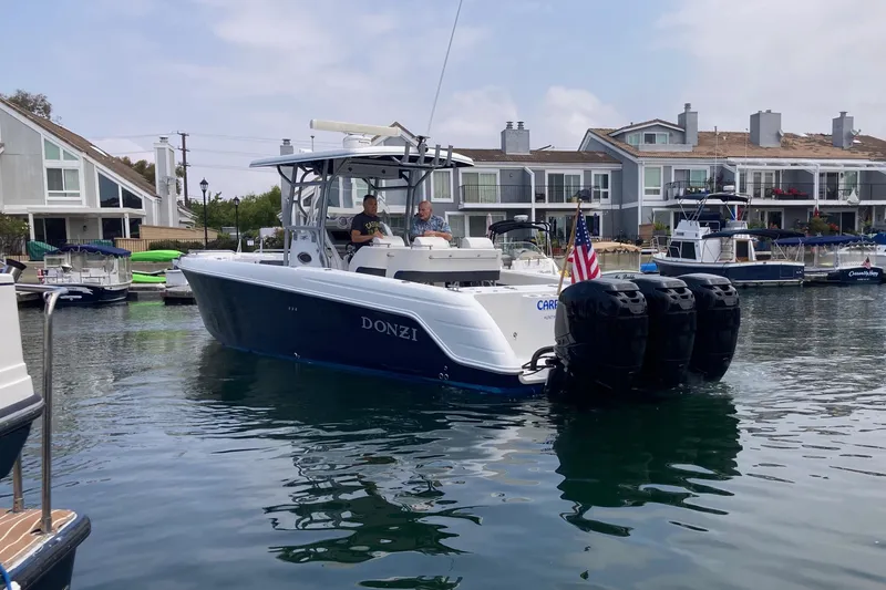 Slide: The Image of 2011 Donzi 38 ZFX Open boat cruising in a marina with waterfront homes. - 7