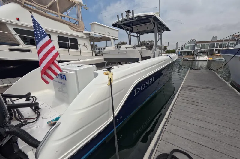 Slide: The Image of 2011 Donzi 38 ZFX Open boat docked, displaying an American flag. - 8