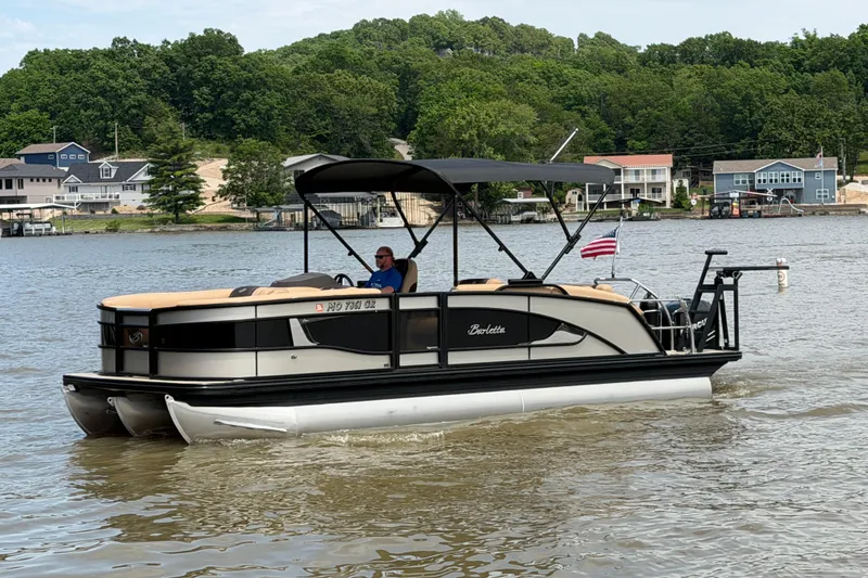 The Image of 2023 Barletta Lusso 23U pontoon boat cruising on a scenic lake. - 0