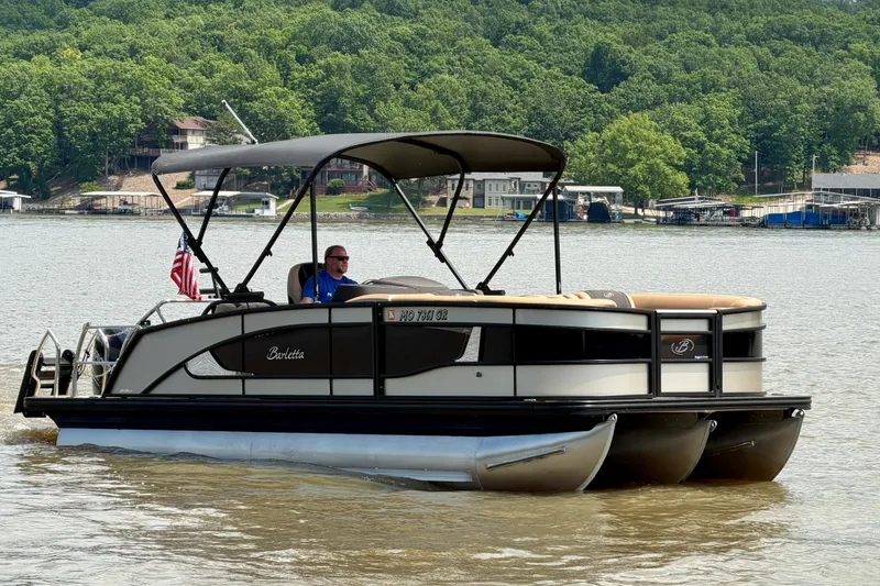 Slide: The Image of 2023 Barletta Lusso 23U pontoon boat cruising on a scenic lake. - 2
