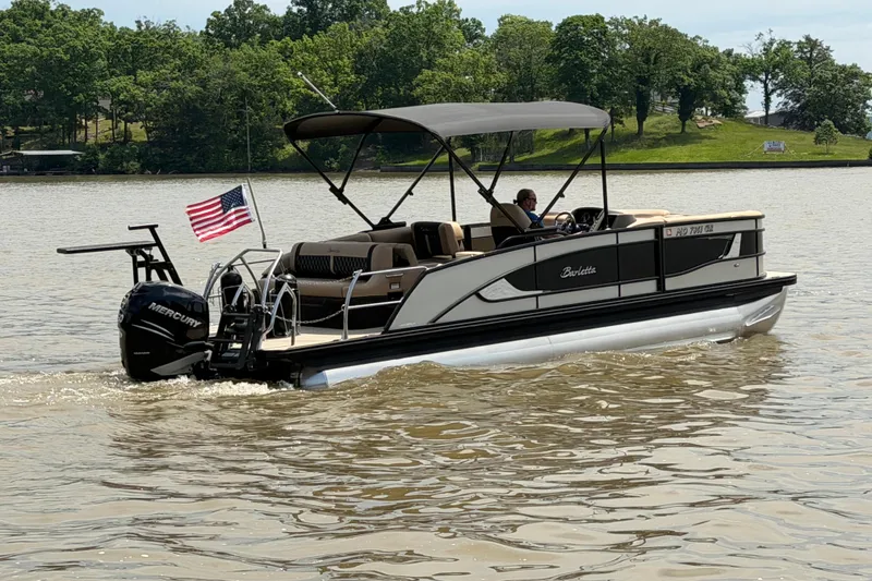 Slide: The Image of 2023 Barletta Lusso 23U pontoon boat cruising on a lake with American flag. - 4