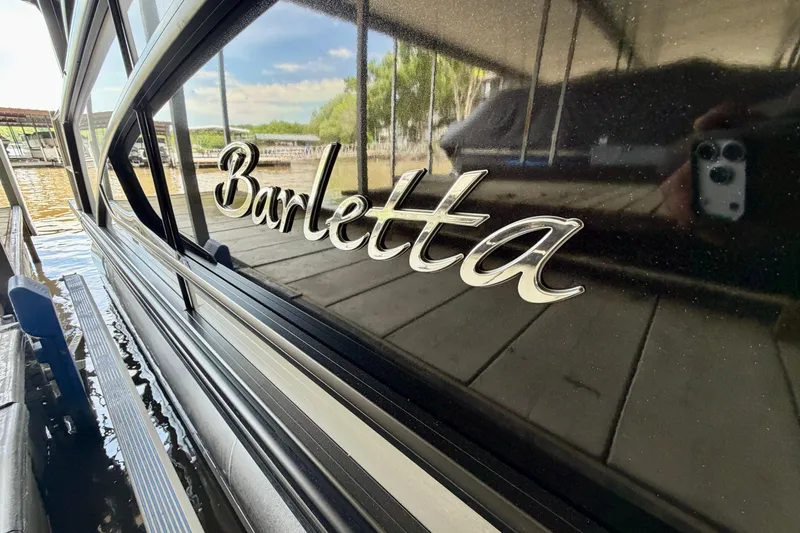 Slide: The Image of 2023 Barletta Lusso 23U boat with reflective black exterior near a dock. - 40