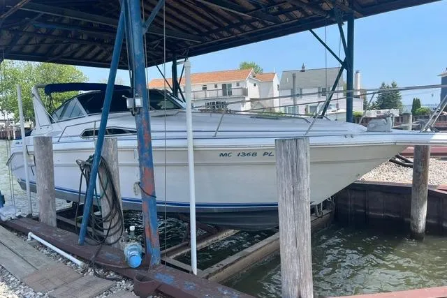 The Image of 1993 Sea Ray Sundancer 330 docked under a covered marina, showcasing sleek design and white exterior. - 1