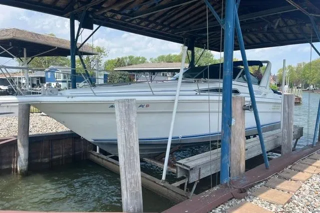 Slide: The Image of 1993 Sea Ray Sundancer 330 docked under a covered marina on a sunny day. - 2