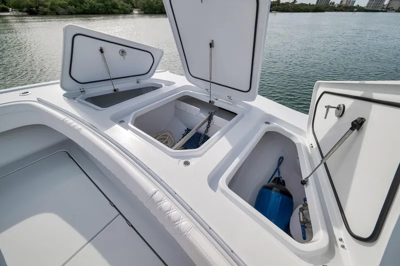 Slide: The Image of 2024 Costa Custom Boats 34SV storage compartments open on deck, near water. - 19