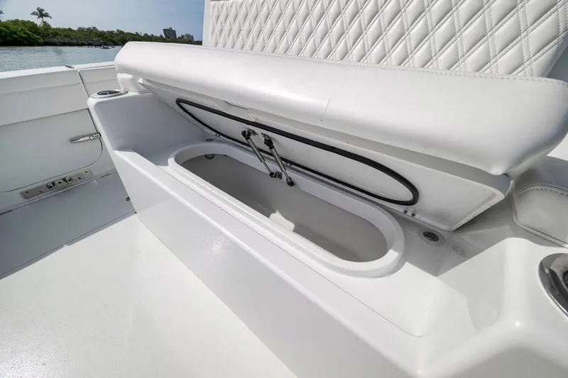 Slide: The Image of 2024 Costa Custom Boats 34SV storage compartment with cushioned seating, open on a sunny day. - 43