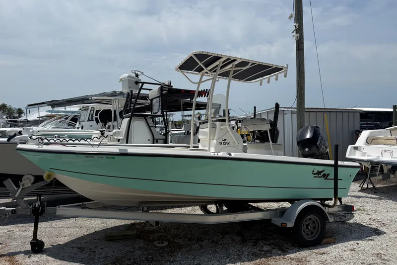 Slide: The Image of 2017 Mako 19 CPX boat on trailer, parked in a marina with other boats. - 2